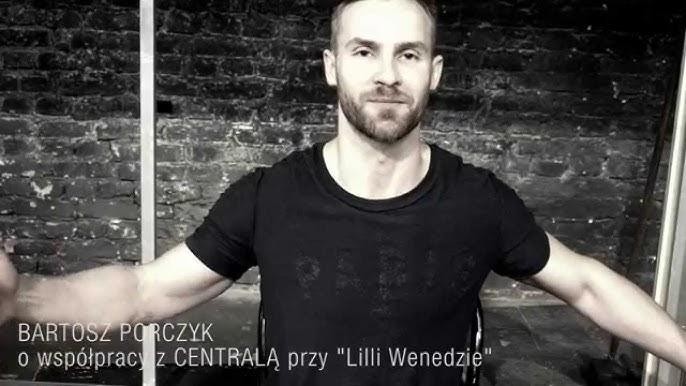 Dynamiczne ujęcie Bartosza Porczyka na scenie teatralnej, oświetlonego dramatycznym światłem, wyrażającego intensywne emocje podczas występu, z subtelnie widocznymi elementami scenografii w tle.
