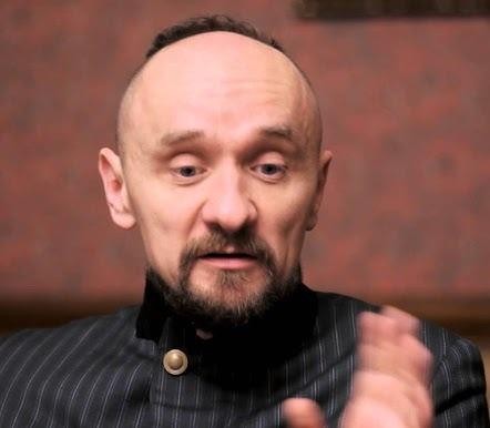 Dynamiczna scena teatralna przedstawiająca spektakl w reżyserii Jana Klaty, z aktorami w ruchu i dramatycznym oświetleniem, oddająca innowacyjny charakter jego twórczości.