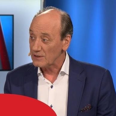 Dariusz Szpakowski, komentujący mecz piłkarski z pełnym zaangażowaniem w boksie komentatorskim na stadionie.