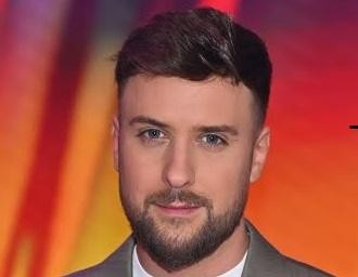 Alt: Aleksander Sikora – prezenter telewizyjny w studiu, dynamiczna poza, profesjonalny strój, symbolizujący jego aktywną rolę w mediach.
