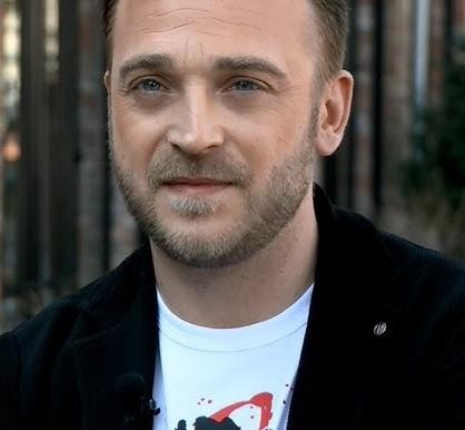 Mateusz Gessler w akcji w profesjonalnej kuchni, skupiony na gotowaniu lub serwowaniu dania, z widoczną pasją i energią.