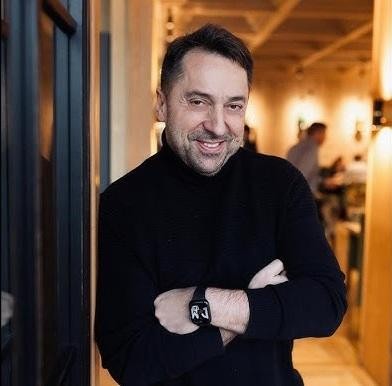 Marcin Miller, uśmiechnięty, w trakcie występu, trzymający mikrofon, z dynamicznym tłem scenicznym.