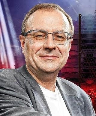 Antoni Dudek podczas wykładu lub publicznego wystąpienia, aktywnie gestykulujący, co podkreśla jego rolę jako publicznego intelektualisty i komunikatora historii.