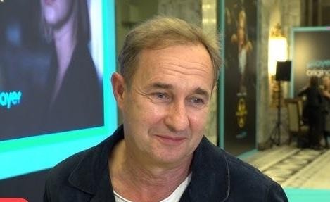 Malowniczy krajobraz Puszczy Kampinoskiej, ukazujący jej spokój i piękno, z wysokimi drzewami i promieniami słońca przenikającymi przez liście.