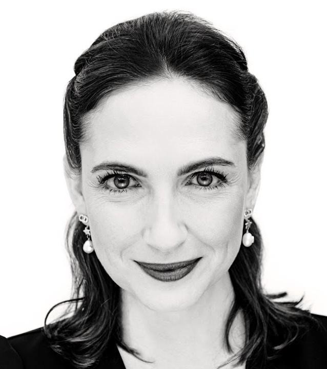 Portret Anny Cieślak, aktorki, z ciepłym uśmiechem i delikatnym tłem teatralnym.