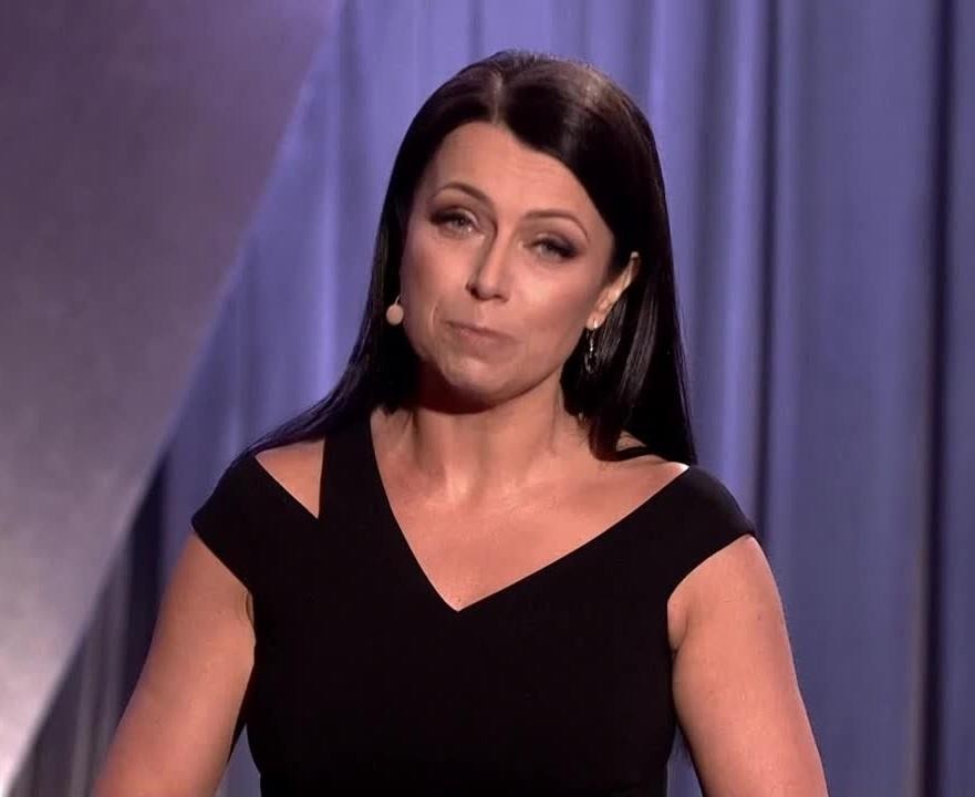 Adrianna Borek w swobodnej pozie za kulisami, uśmiechnięta, w otoczeniu rekwizytów scenicznych.