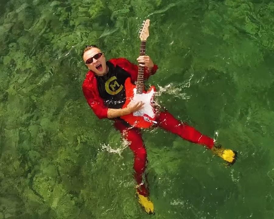 Czadoman w trakcie występu na scenie, otoczony kolorowymi światłami, w dynamicznej pozie.