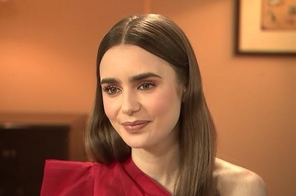 Lily Collins na planie filmowym, w kostiumie, otoczona sprzętem filmowym, skupiona na pracy.