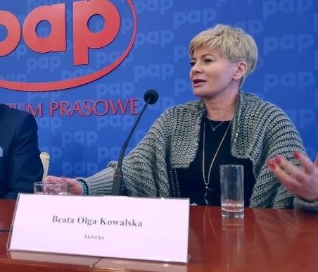 Beata Olga Kowalska w dynamicznej akcji podczas występu teatralnego lub nagrania telewizyjnego, ukazująca jej energię i zaangażowanie.