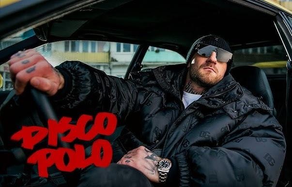 Kizo z batonem Kizzers i pizzą Sukcesiliana, symbolizujące jego sukcesy muzyczne i przedsiębiorcze.